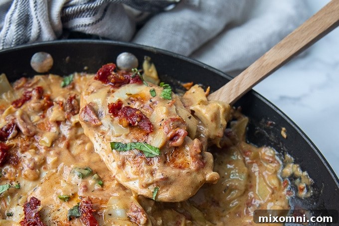 Closer angle shot of a spoonful of low-carb sun-dried tomato chicken with creamy sauce.