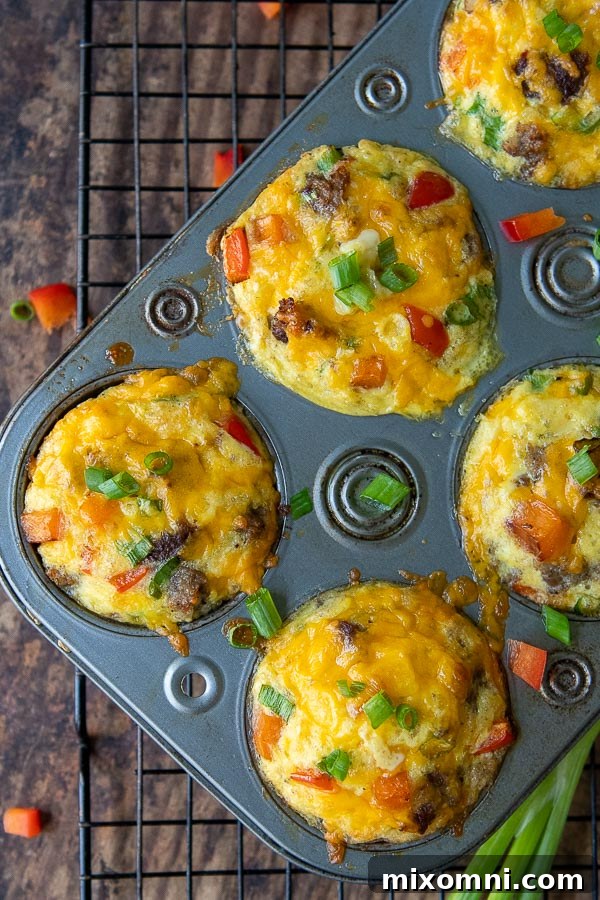 Freshly baked breakfast egg muffins in a muffin tin, with chopped bell pepper scattered around.