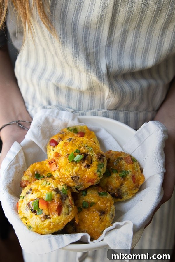 Someone holding a rustic bowl filled with ready-to-serve breakfast egg muffins.