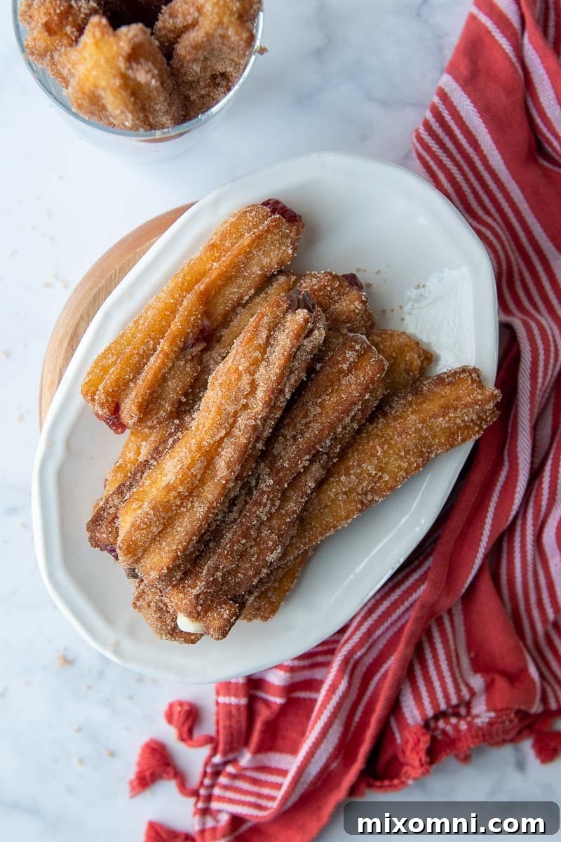 An overhead shot showcasing a beautiful arrangement of gluten-free churros on a white plate, with a stylish red dish towel providing a pop of color.