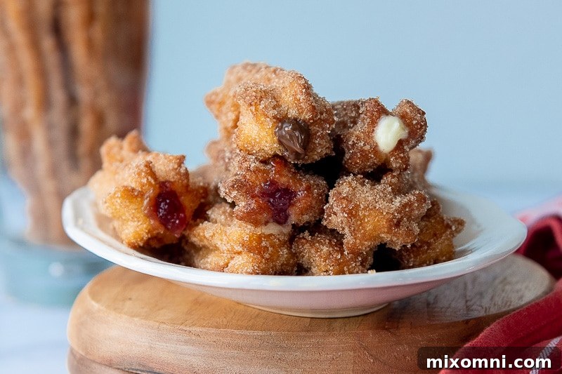 A delectable close-up of various stuffed churros, showcasing gooey chocolate, sweet jelly, and creamy fillings peeking out from the ends.
