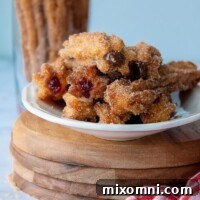 straight on shot of a plate full of filled stuffed churros with a red towel laying next to it