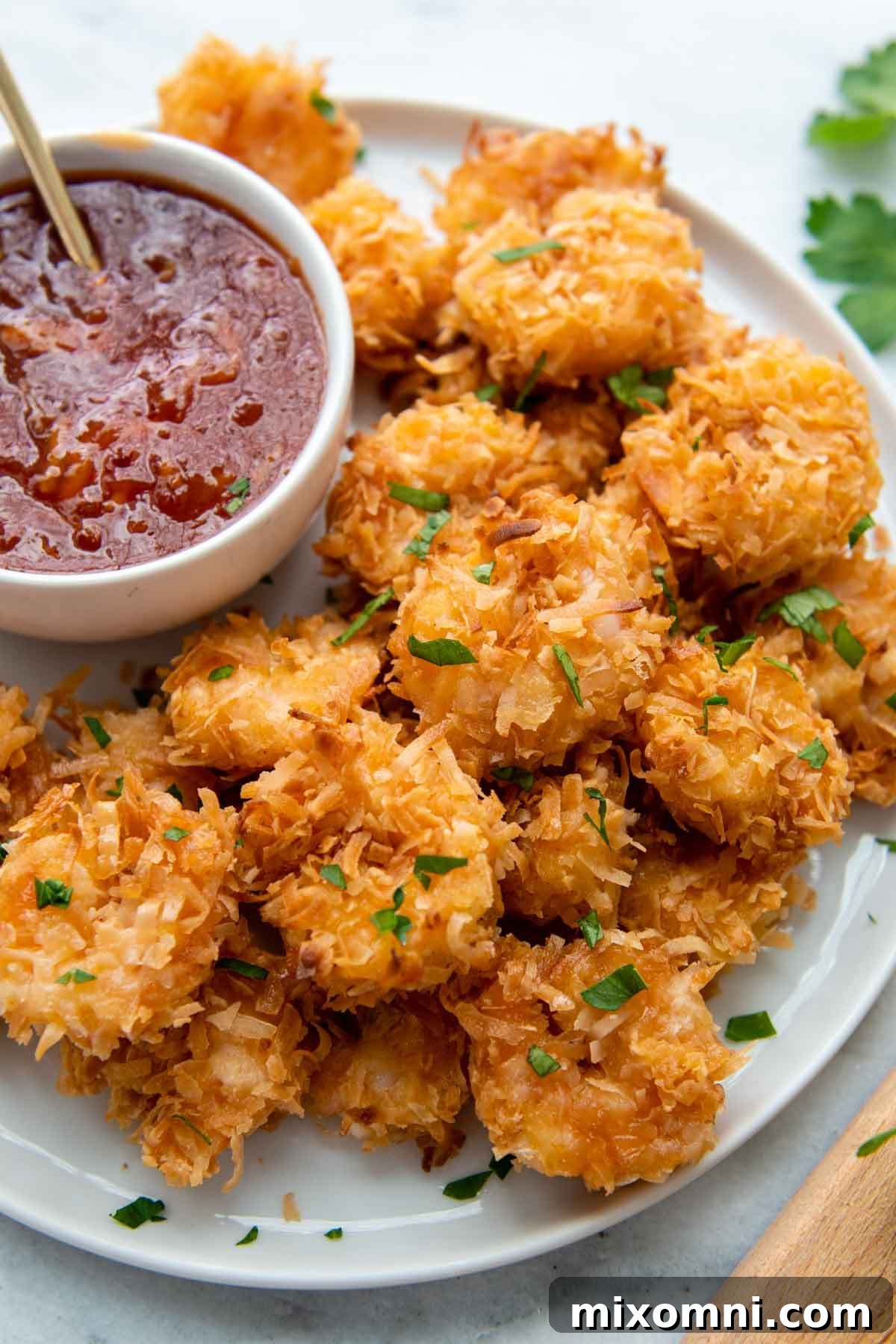 A beautifully arranged plate of crispy, golden gluten-free coconut shrimp, ready to be enjoyed, with a vibrant dipping sauce alongside.