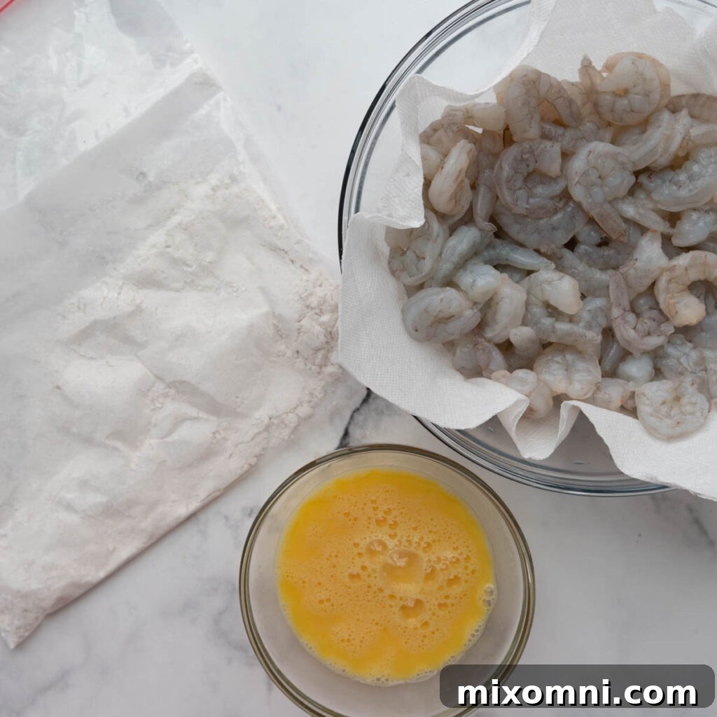 All the necessary ingredients for preparing gluten-free coconut shrimp laid out, including shrimp, eggs, coconut flakes, and seasonings, ready for the breading process.