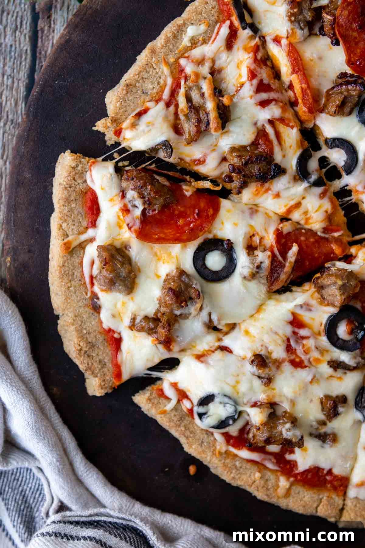 An overhead shot of a freshly sliced almond flour pizza, ready to be served, showcasing its generous toppings and perfect golden crust.