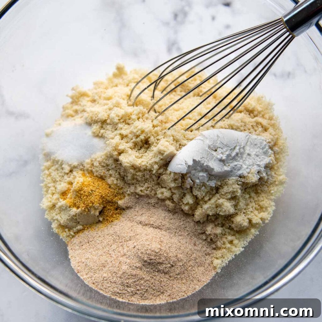 Dry ingredients for almond flour pizza crust being whisked together in a mixing bowl.