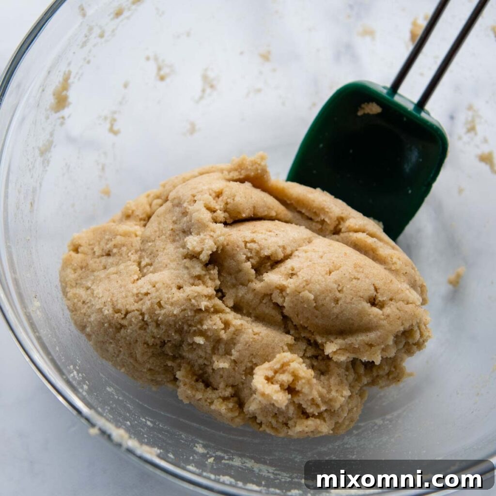 Almond flour pizza dough in a bowl after resting, now firmer and easier to handle, ready to be shaped into a ball.