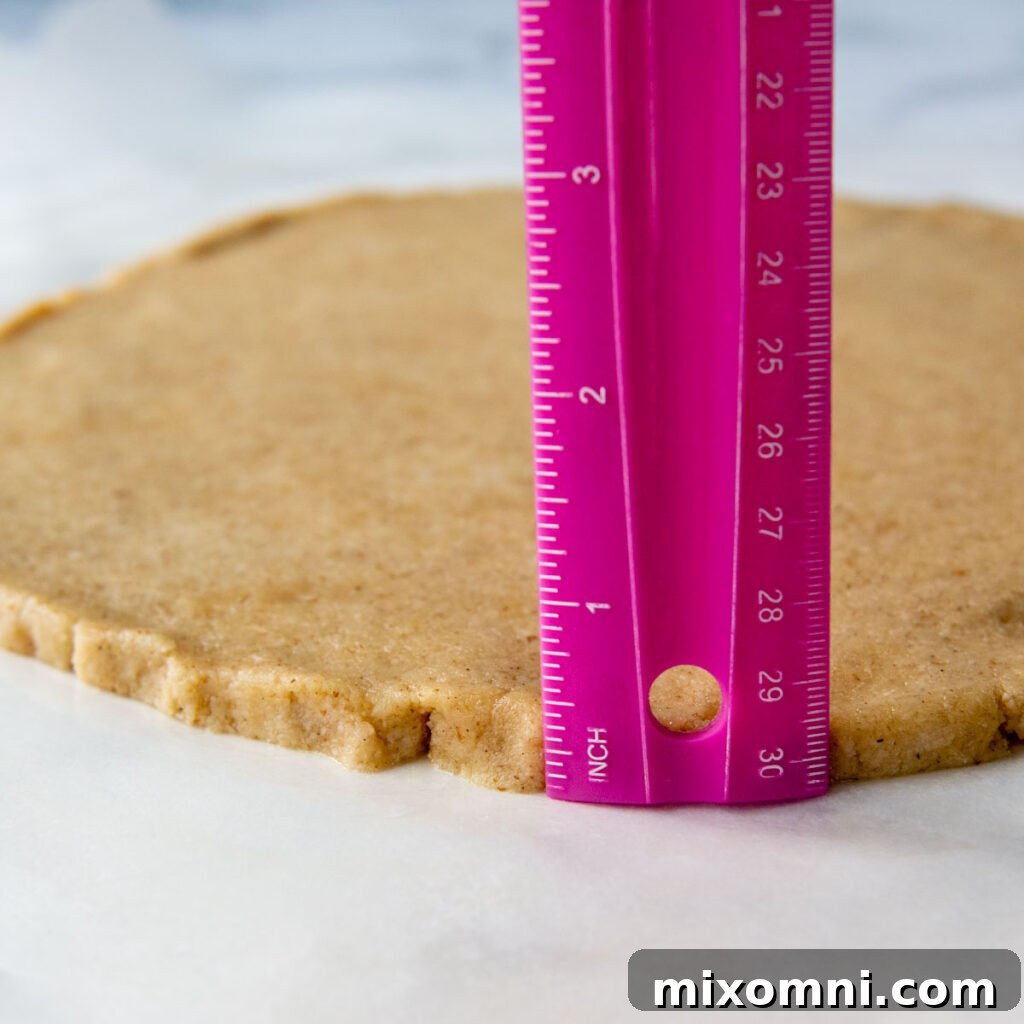 A ruler precisely measuring the thickness of the almond flour pizza crust, indicating it's about 1/4 to 1/2 inch thick.