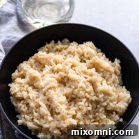 risotto in a black bowl with wine glasses behind it.