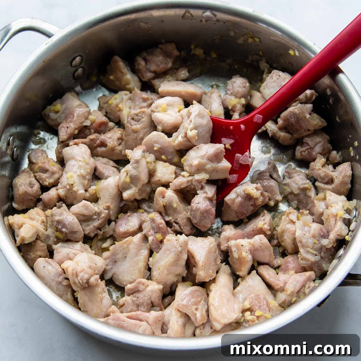 Chicken thighs, shallots, and ginger sizzling in a deep skillet, beginning to cook and release their aromas.