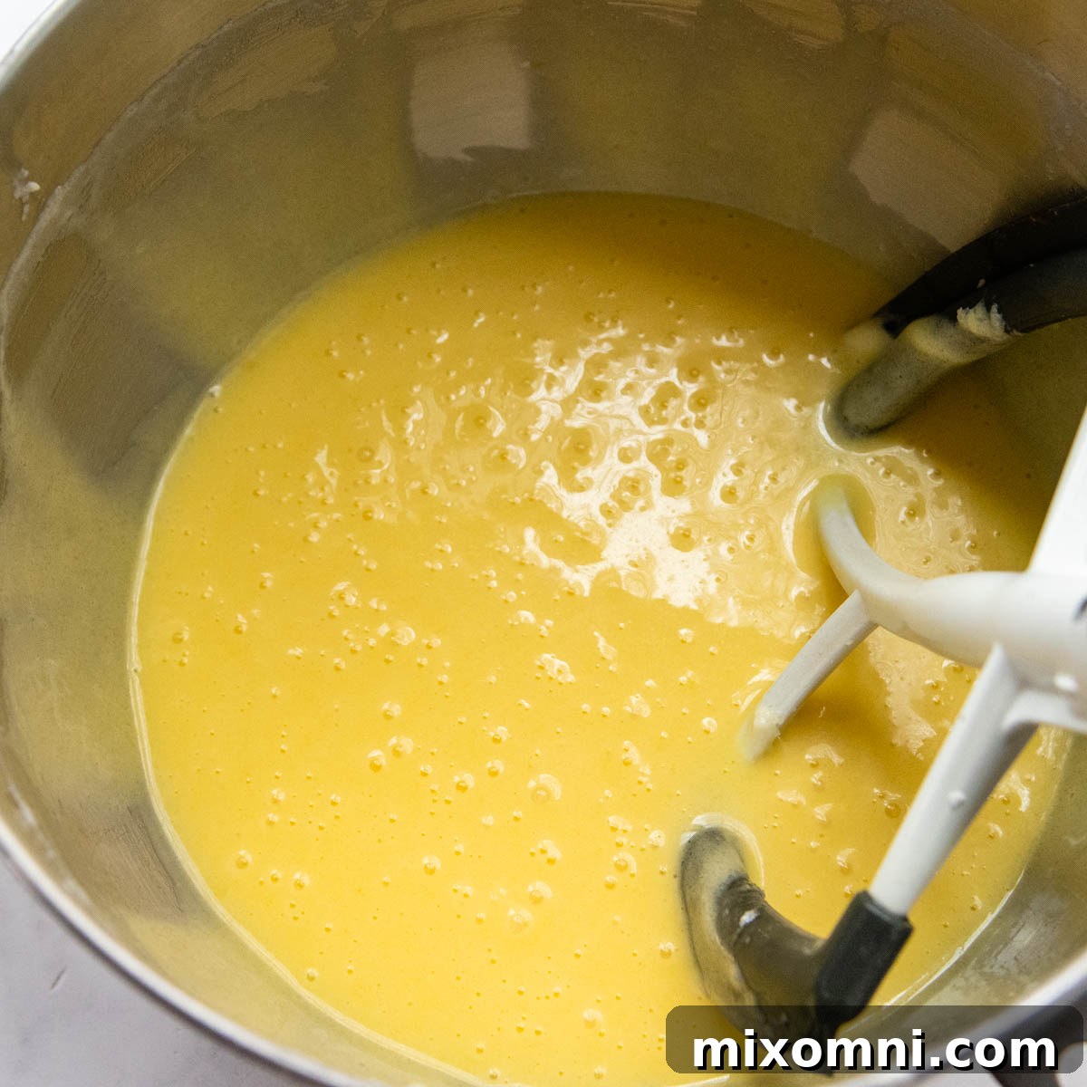 The pound cake batter after eggs and vanilla extract have been mixed in, appearing thinner.