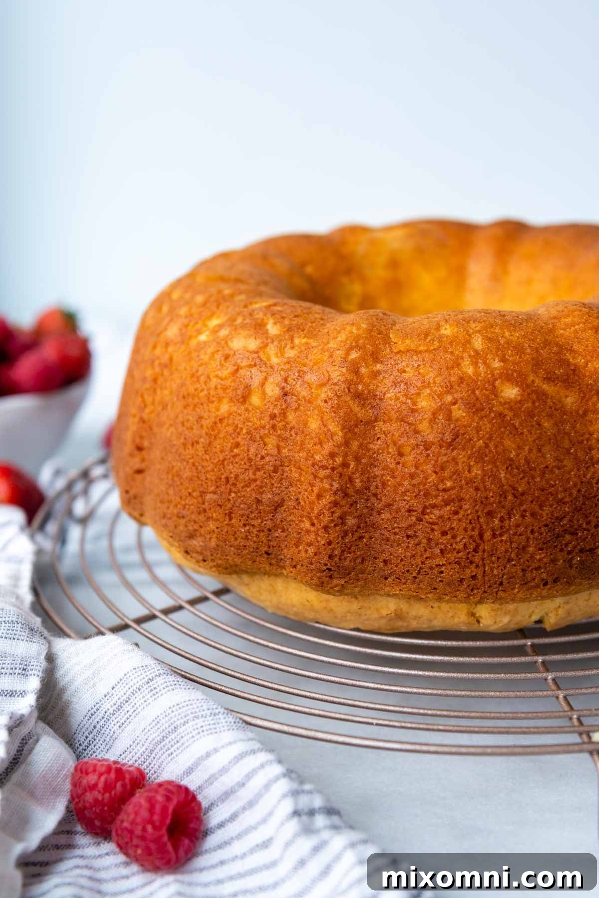 A freshly baked gluten-free bundt cake cooling on a wire rack on a marble counter.