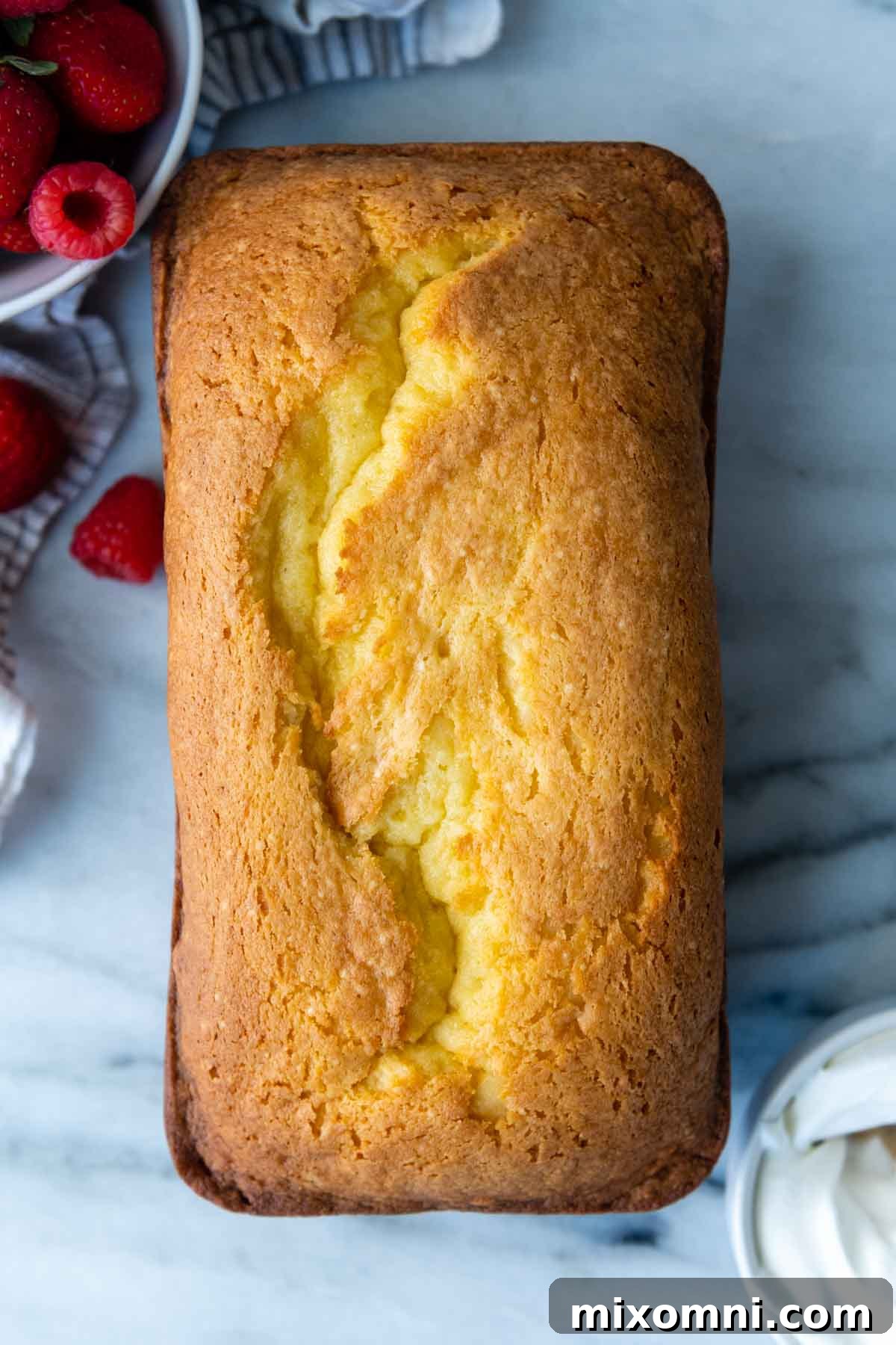 An uncut gluten-free loaf cake resting on a elegant marble slab, showcasing its golden crust.