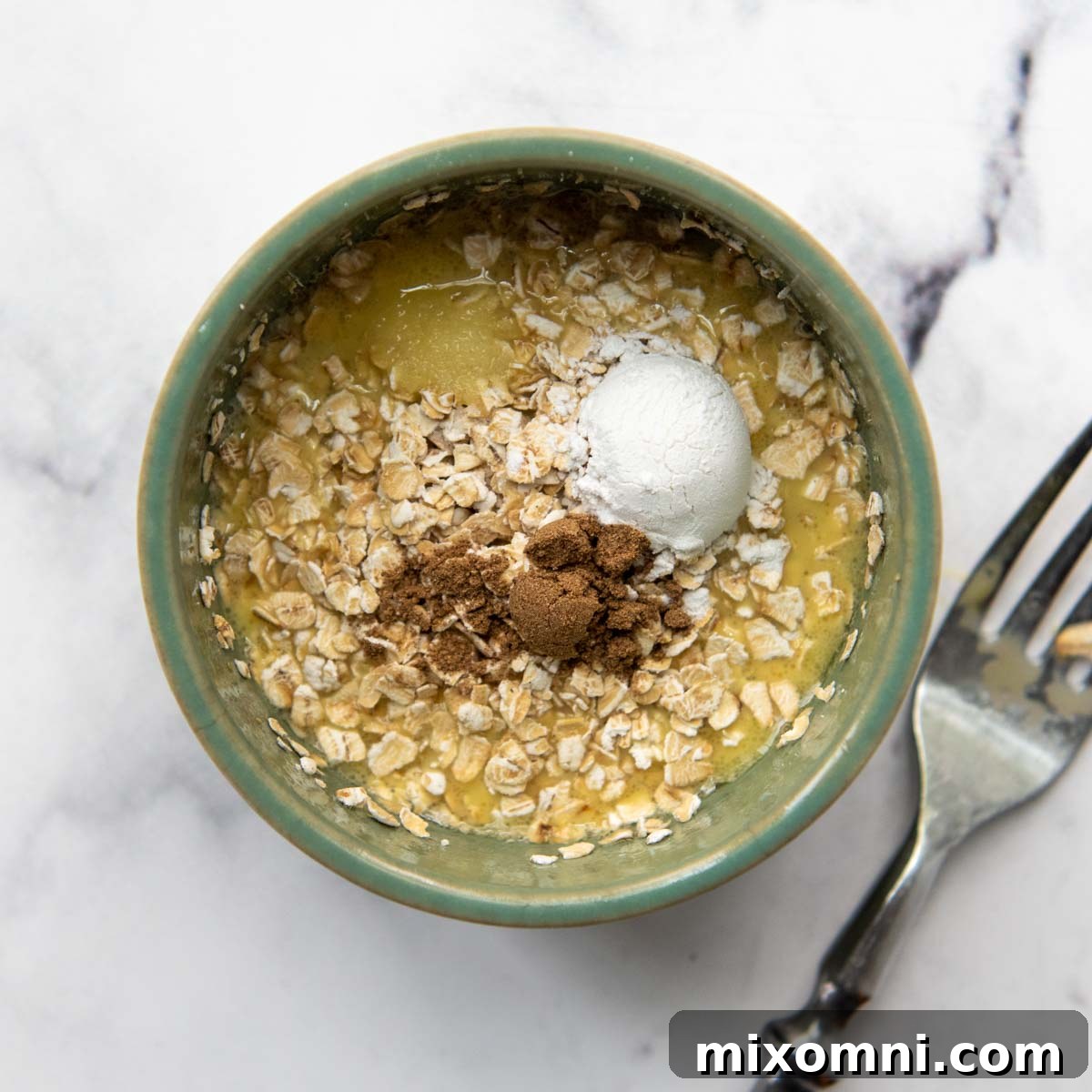 Adding dry ingredients to the wet mixture for the mug cake recipe.