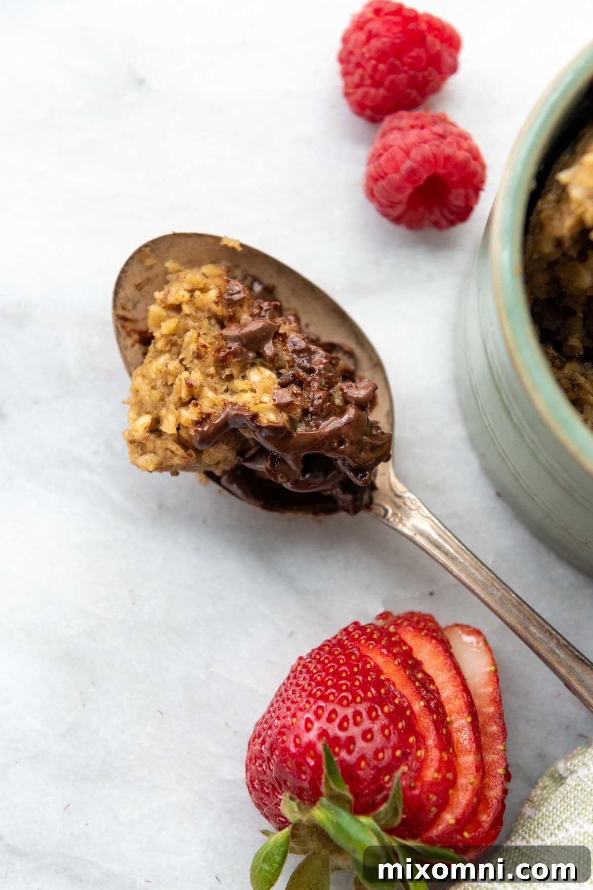 A spoon of the oatmeal mug cake on a white background, highlighting its fluffy texture.