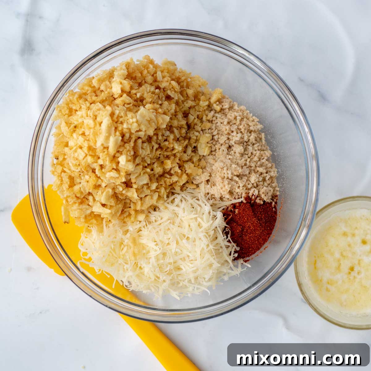 A bowl of crunchy topping ingredients next to melted butter, ready to be combined.