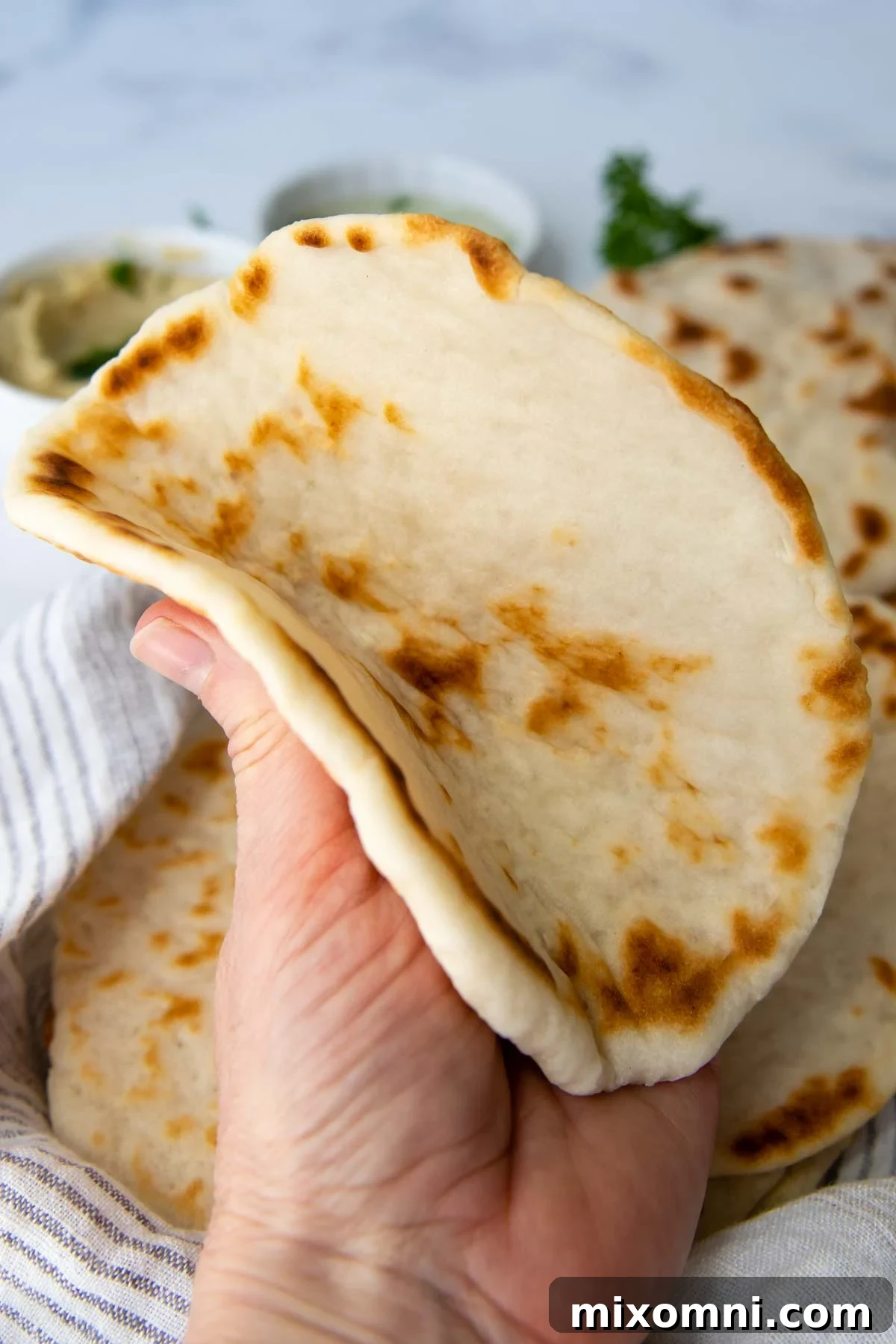 A soft gluten-free flatbread being gently folded, highlighting its flexibility and doughy texture.