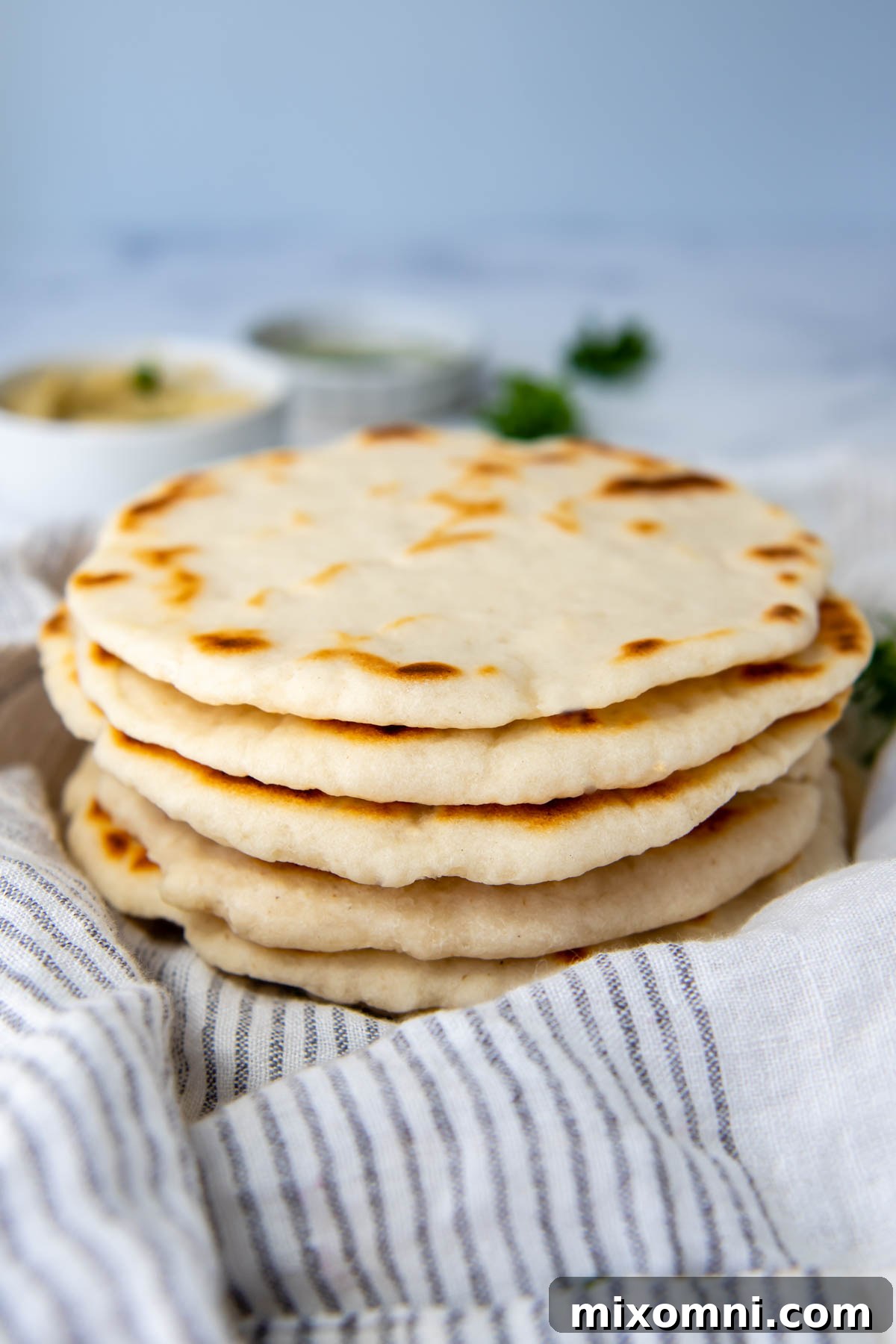 A beautiful stack of freshly cooked gluten-free flatbreads resting on a white kitchen towel, ready to be served.