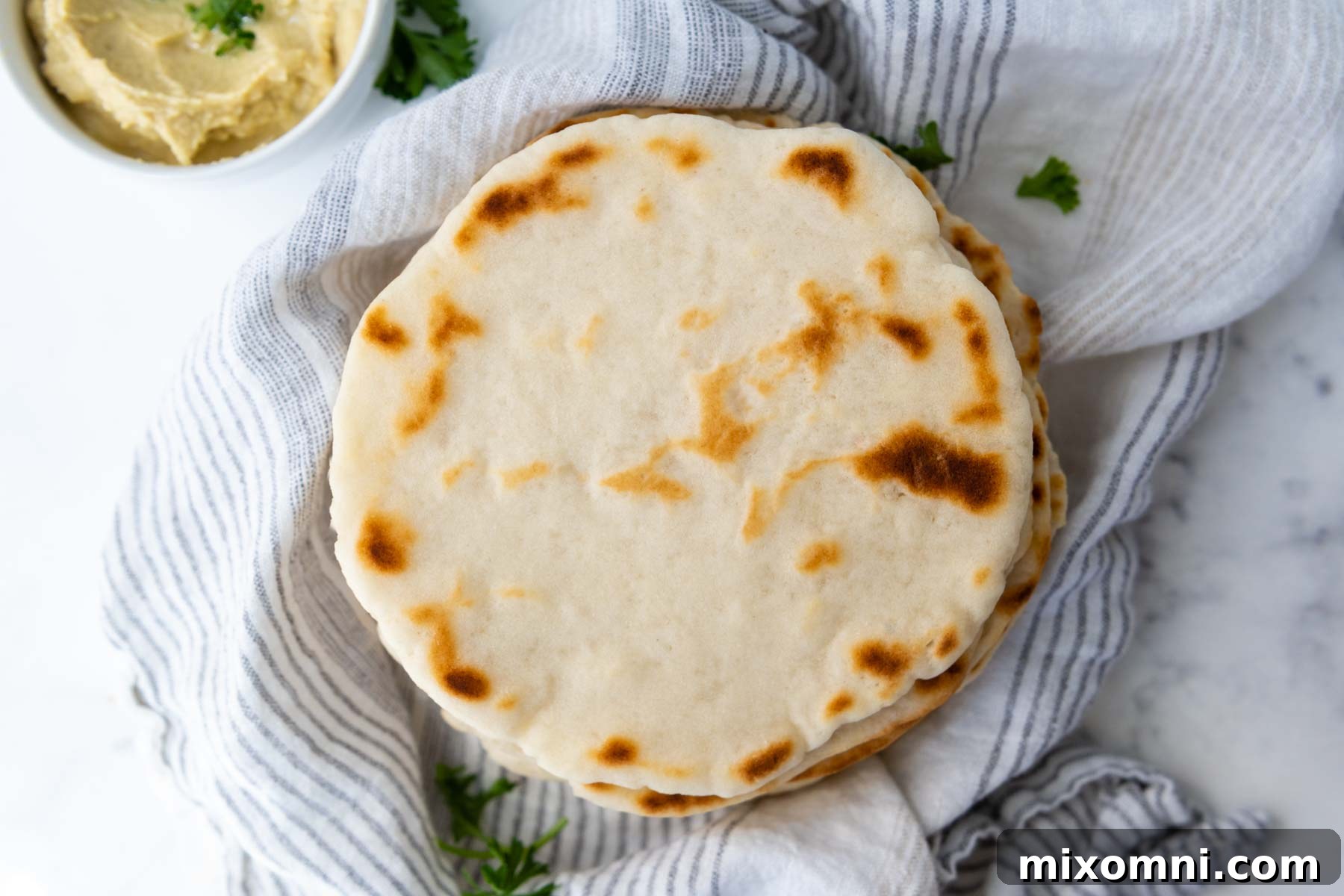 An overhead shot of a freshly baked gluten-free flatbread served alongside a bowl of creamy hummus, inviting dipping.