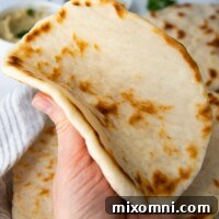 A gluten-free flatbread being folded in half, showcasing its flexibility and soft interior.