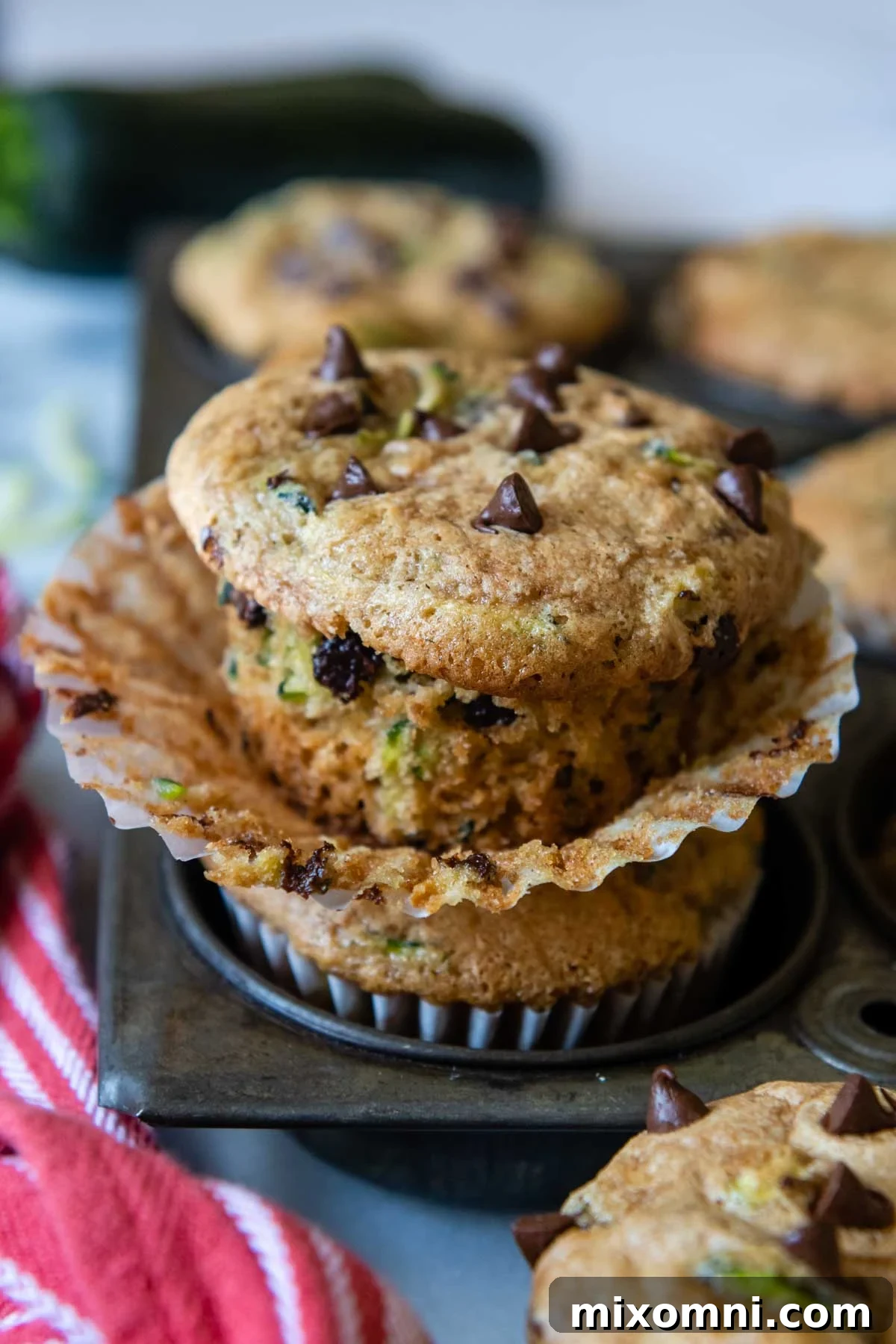 A beautifully baked gluten-free zucchini muffin, unwrapped and ready to eat, resting on a vintage muffin pan.