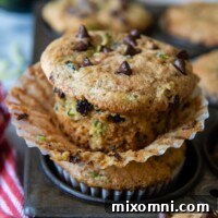 A gluten-free zucchini muffin unwrapped from its liner, sitting on a vintage muffin pan, showcasing its perfect texture.