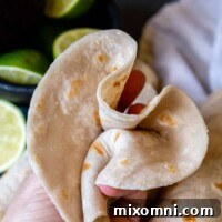 a flour tortilla scrunched up in a hand.