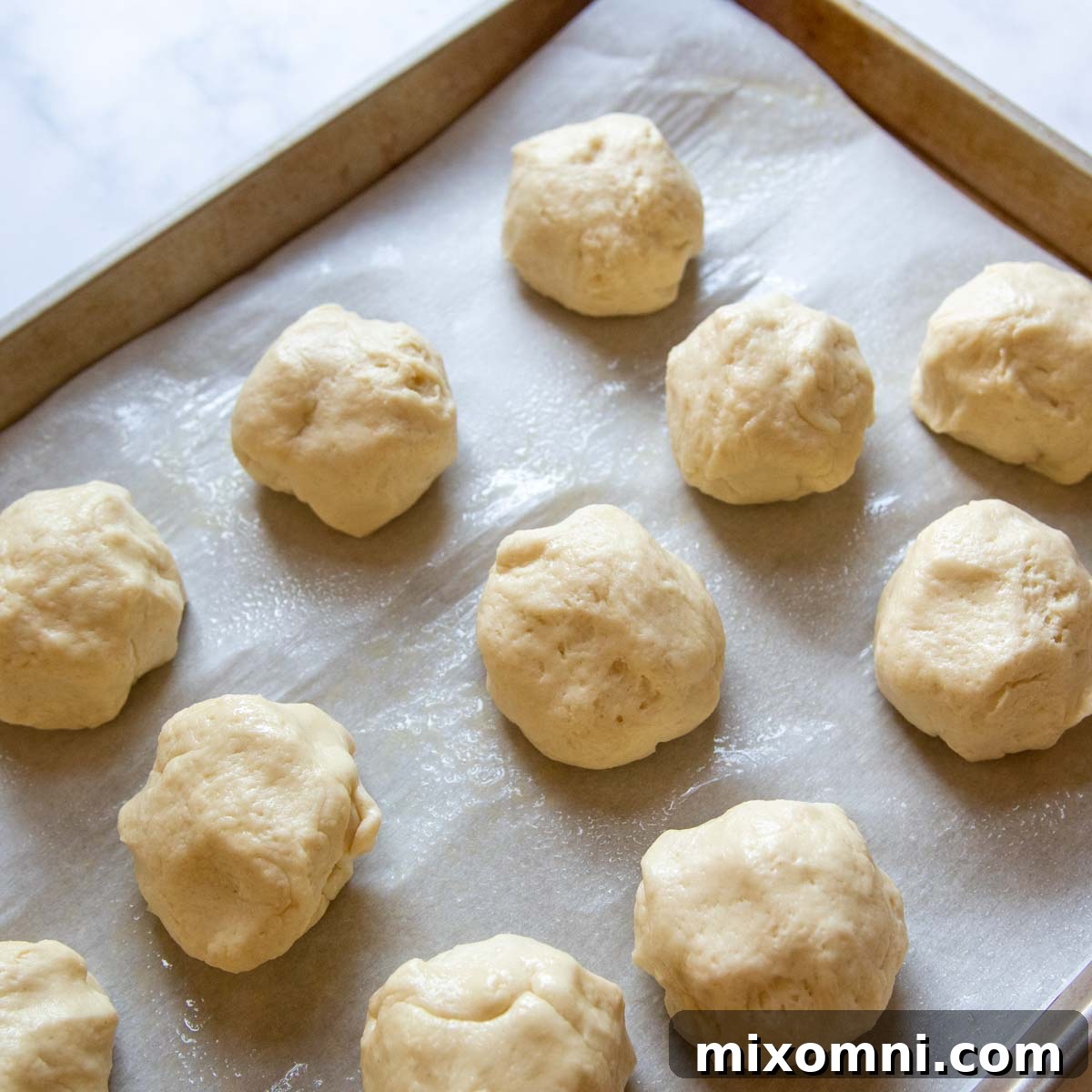 Precisely portioned gluten-free hot dog bun dough balls resting on a baking sheet, ready for the next shaping step.