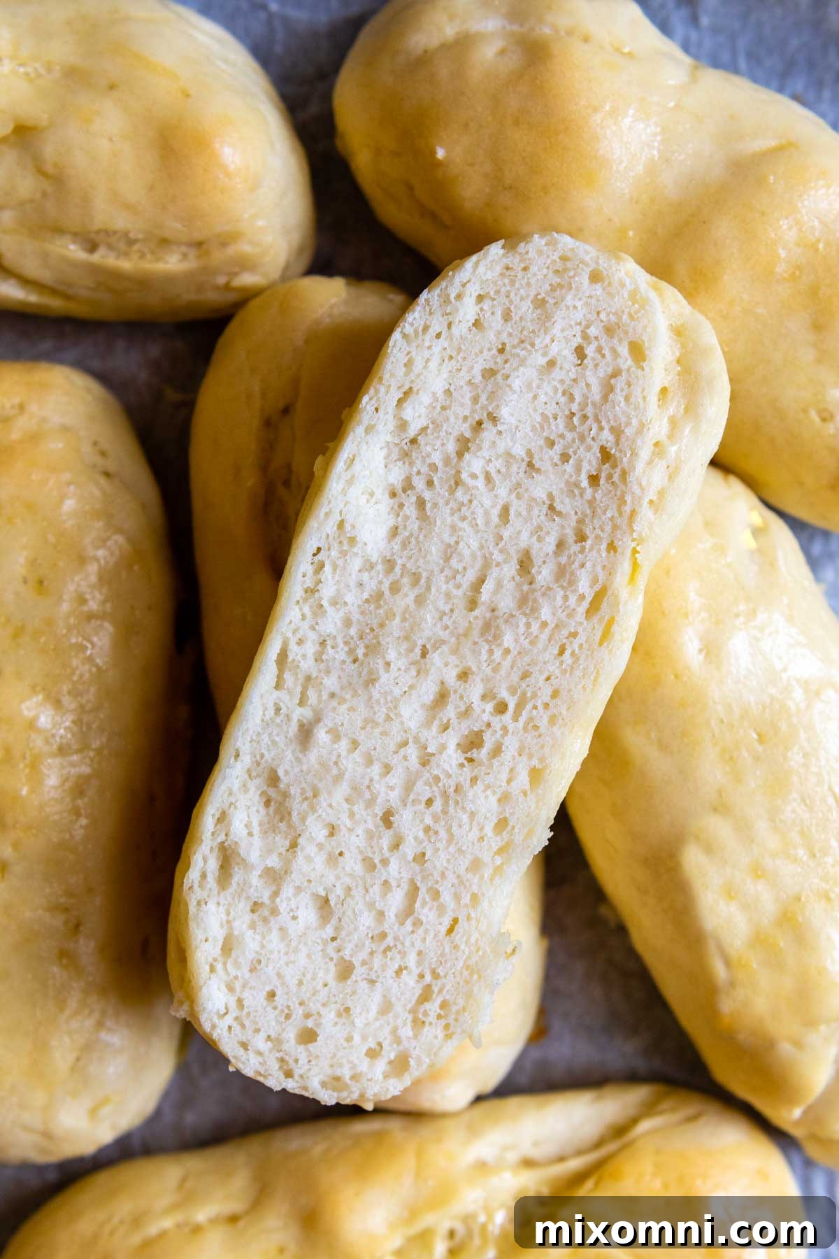 A perfectly baked, golden-brown gluten-free hot dog bun, sliced in half to reveal its incredibly soft, airy interior texture.