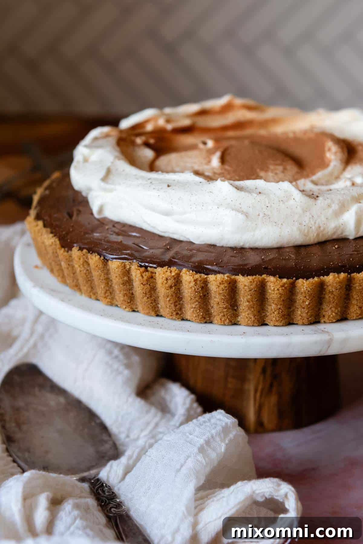 A rich chocolate tart with a perfectly baked gluten-free graham cracker crust, topped with fresh whipped cream and chocolate shavings.