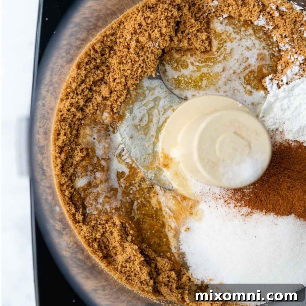 The graham cracker crumbs, sugar, gluten-free flour, and melted butter are combined in a food processor for even mixing.