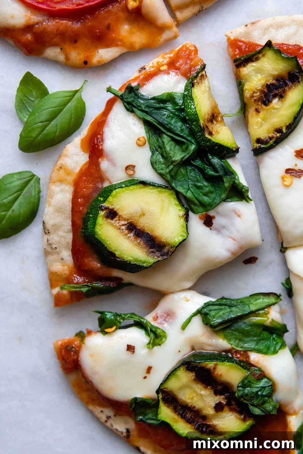 Close-up of a slice of grilled gluten-free pizza, garnished with fresh basil leaves.