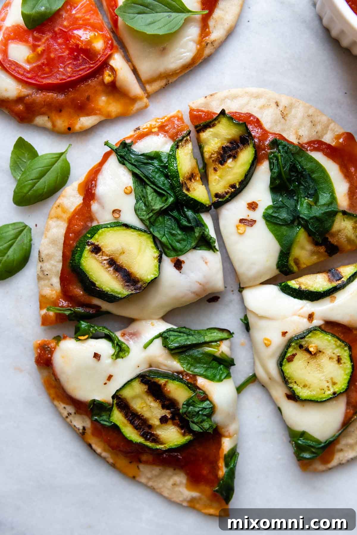Sliced grilled gluten-free pizza topped with fresh zucchini.