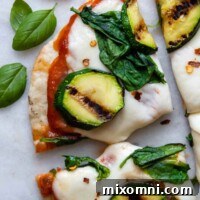 Close-up of a slice of grilled gluten-free pizza with fresh basil leaves next to it.