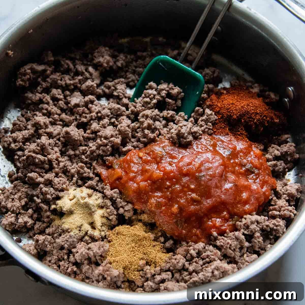 Ground beef browning in a skillet on the stove, ready for seasoning.