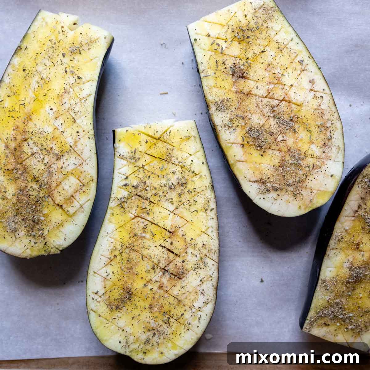 Crosshatch-scored eggplant halves brushed with olive oil and seasoned with spices.