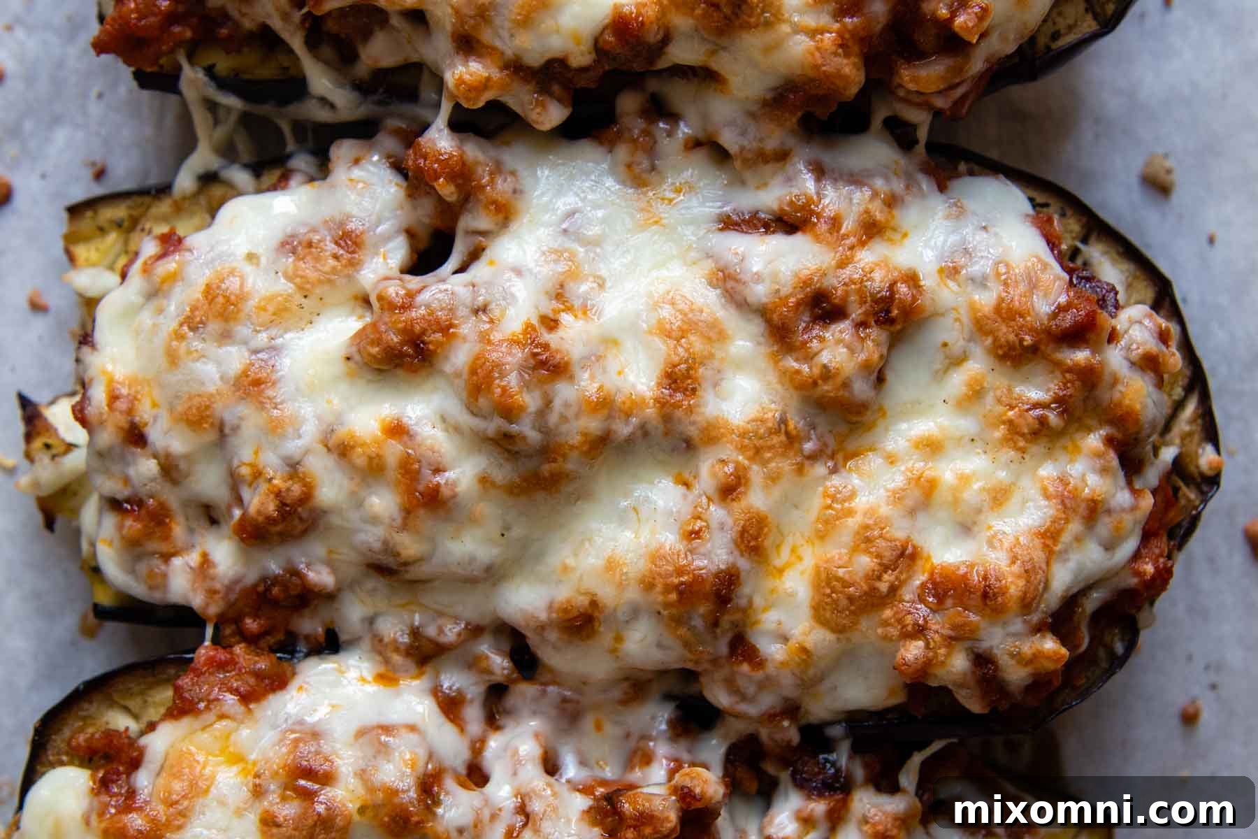 Overhead close-up shot of a single perfectly baked eggplant boat, showcasing the melted cheese, rich filling, and tender eggplant.