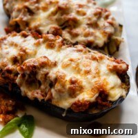 Close up of baked eggplant boats on a white dish, garnished with basil.