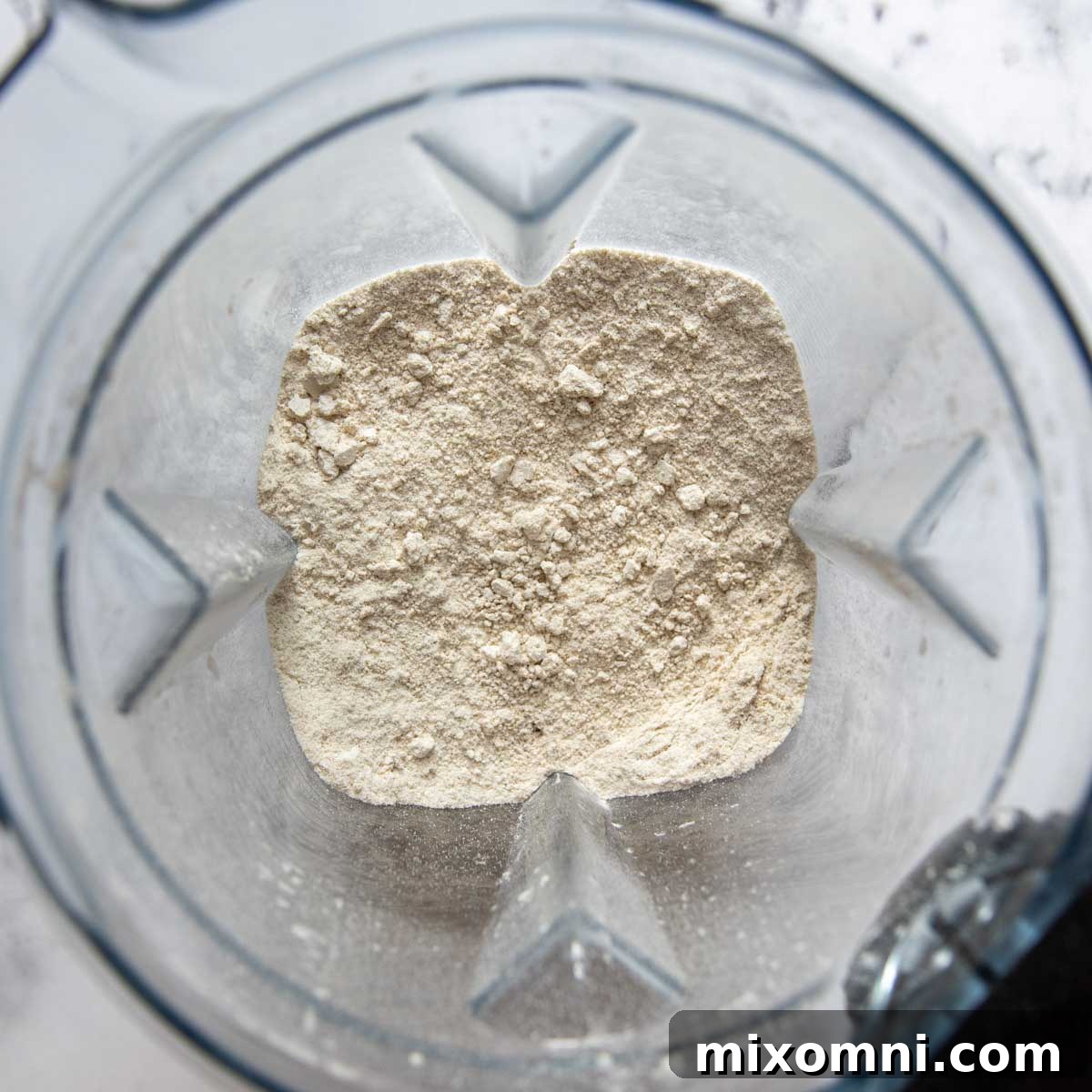Rolled oats being blended in a high-powered blender to create fine oat flour.