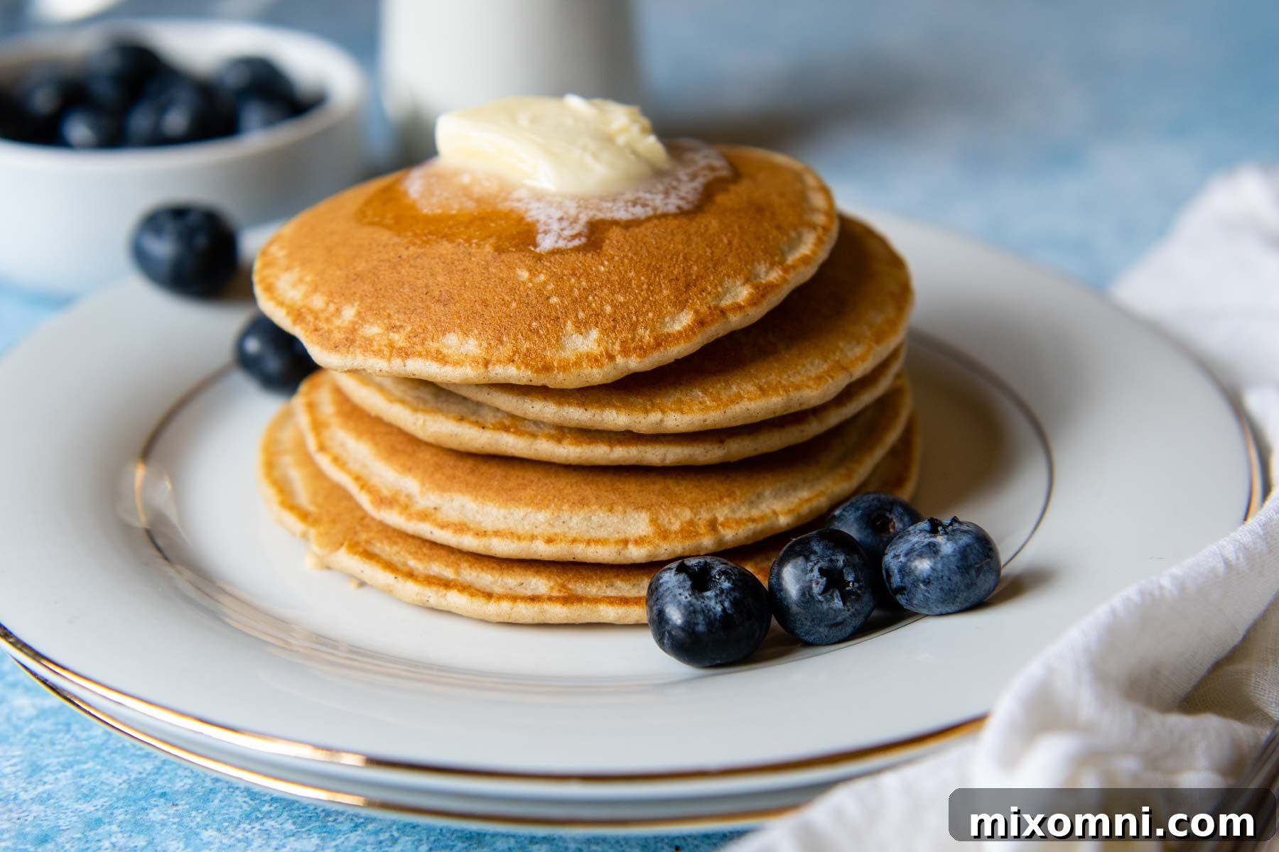 A stack of fluffy oat flour pancakes with a pat of butter melting on top, ready to be served.