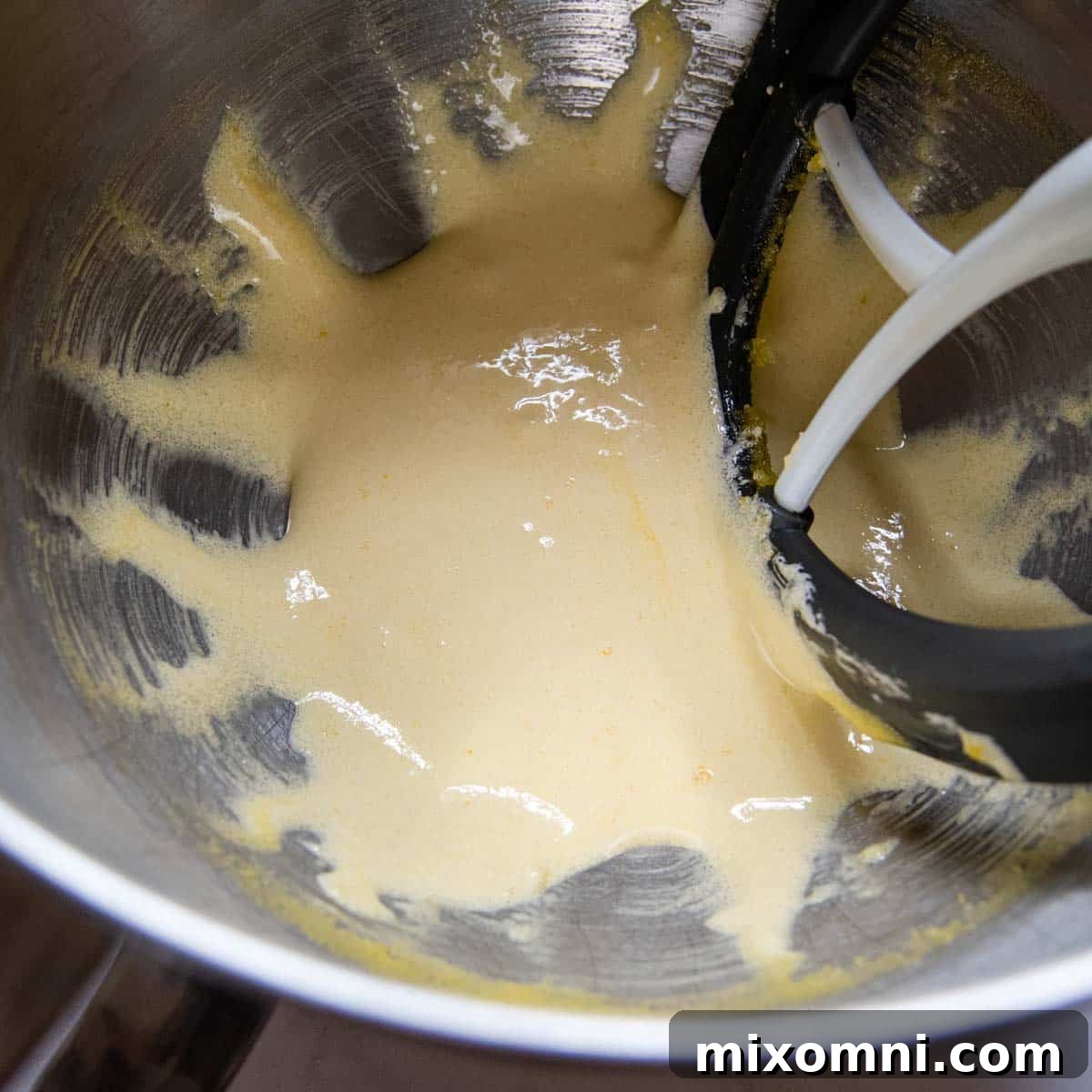 Egg yolks and sugar being beaten together in a bowl until pale and thick.