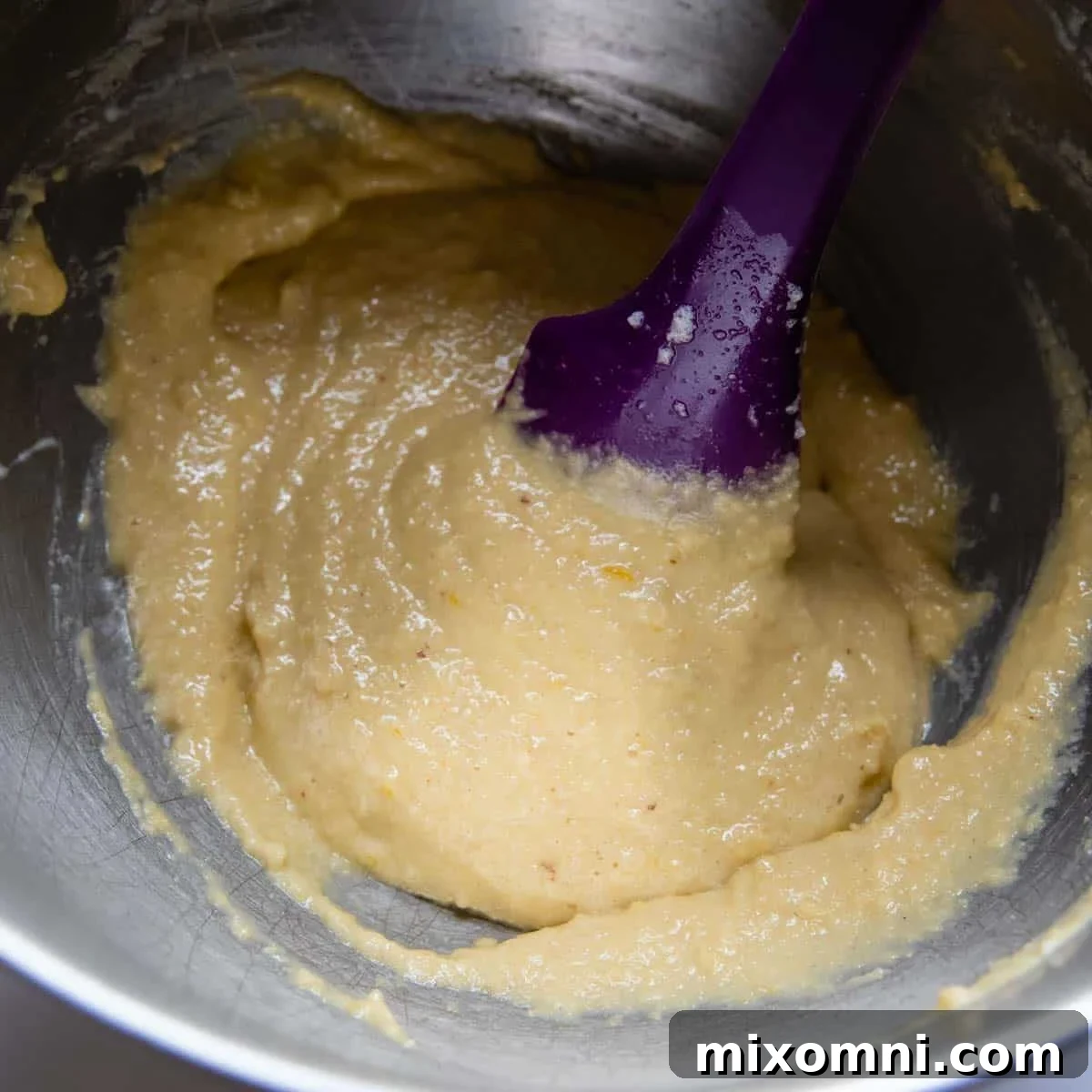 Egg whites being gently folded into the cake batter, showing the lightening texture.