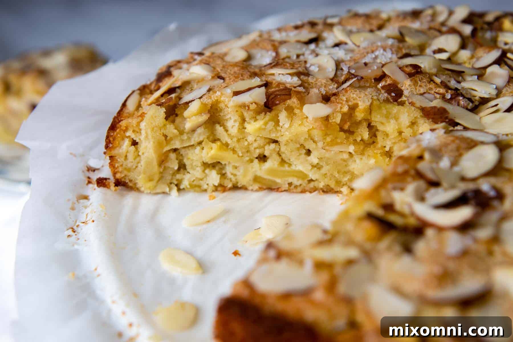 The interior texture of a slice of almond flour apple cake, showing apples and a light crumb, on a platter.