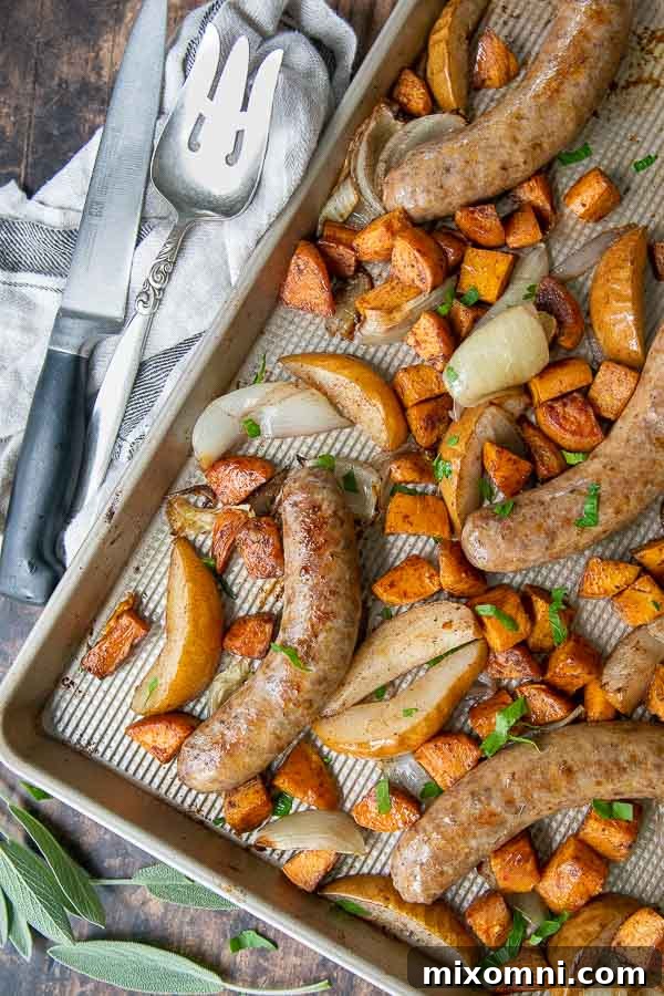 Overhead shot of a vibrant sheet pan sausage bake with sweet potatoes, onions, and pears, perfectly roasted and ready to serve.