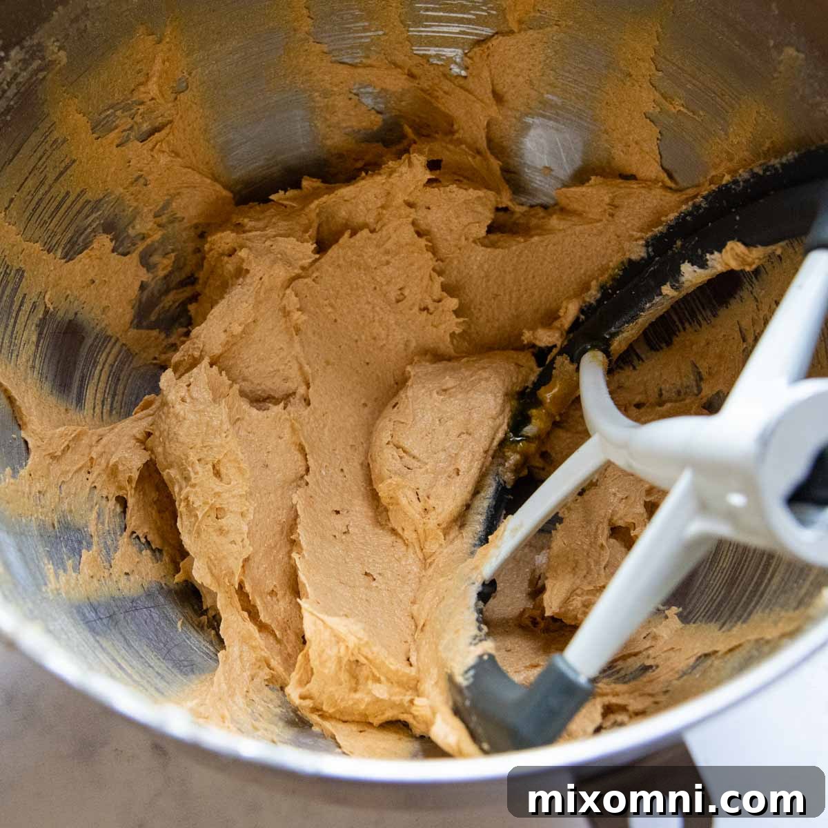 Smooth and well-combined cookie dough mixture in a mixing bowl, featuring pumpkin puree, butter, sugar, and other wet ingredients.