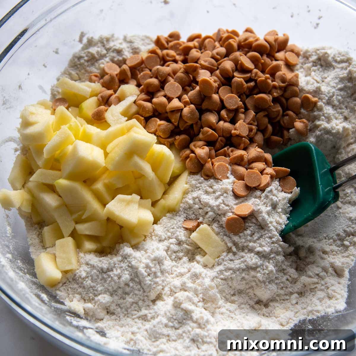 Diced apples and butterscotch chips being stirred into the flour and butter mixture.