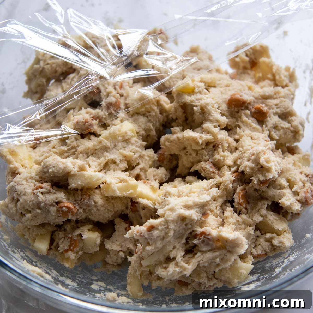 A bowl of scone dough covered with plastic wrap, chilling in the refrigerator.
