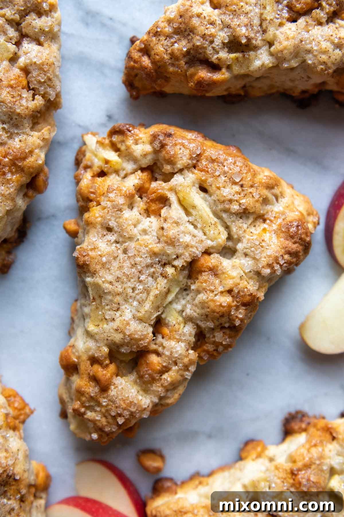 Overhead shot of freshly baked gluten-free apple scones arranged on a cooling rack, with apple slices nearby.