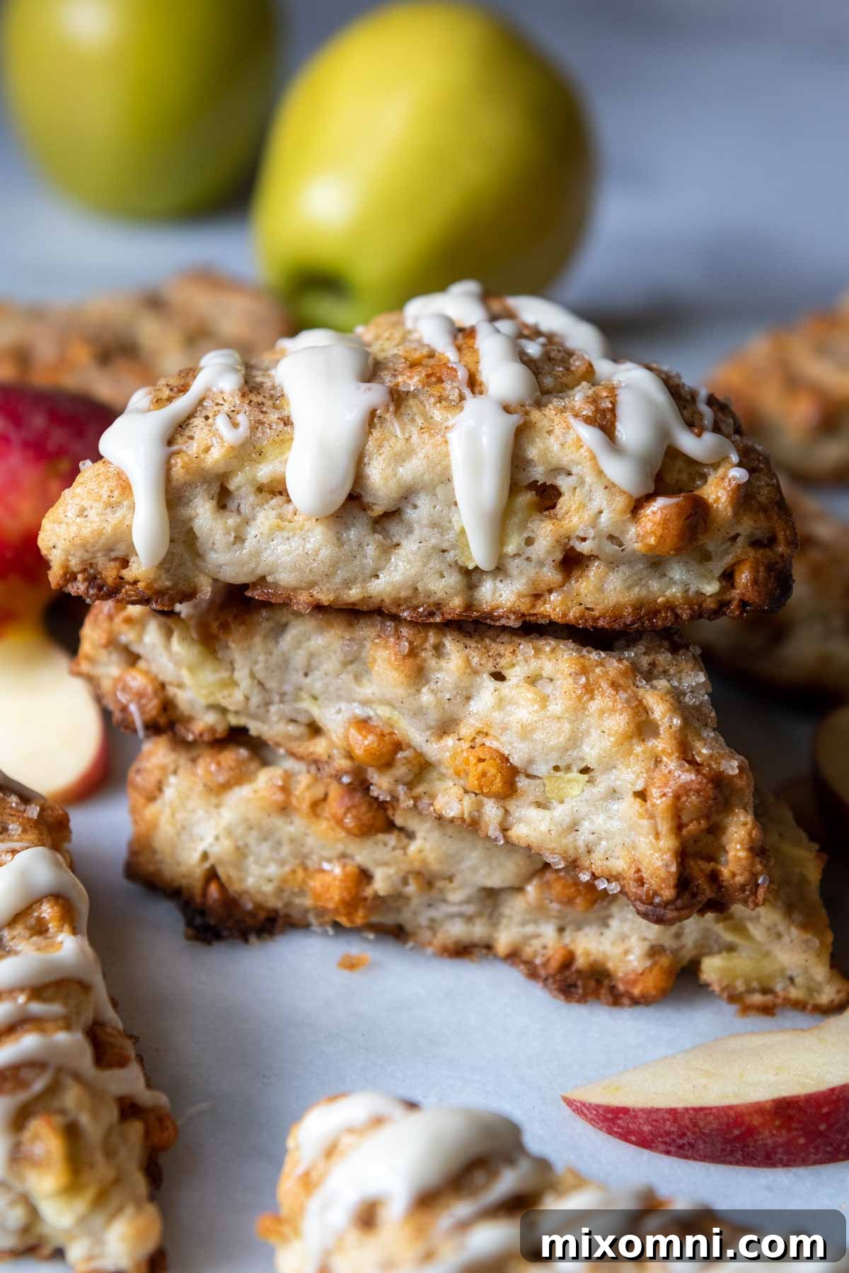A stack of golden gluten-free apple scones, with a luscious glaze drizzled over the top one.