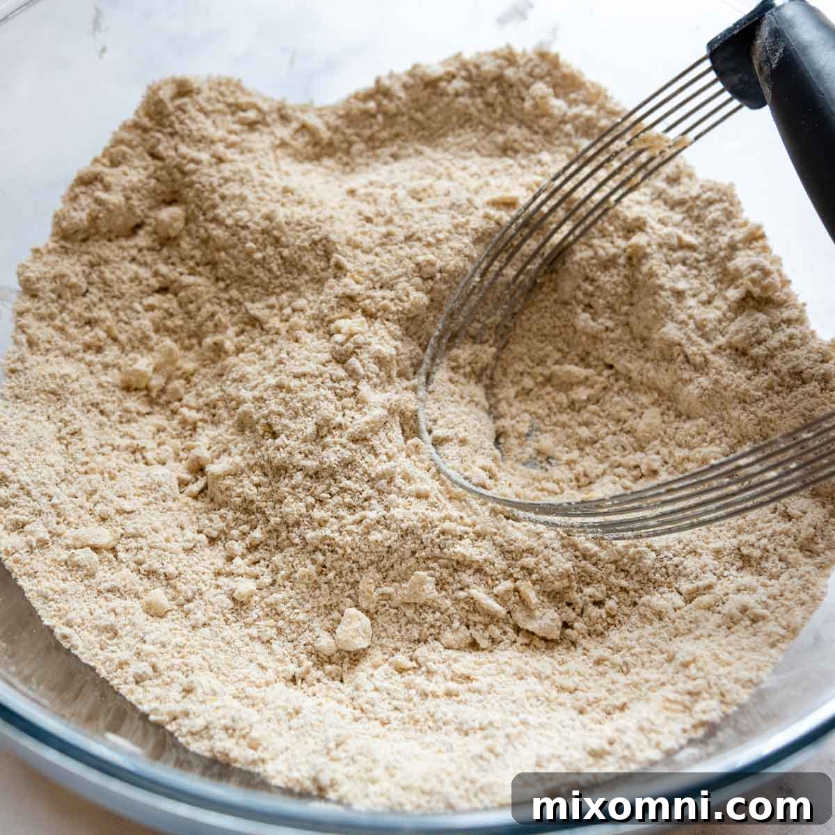 Oat flour blended with small pieces of cold butter, showcasing the initial mixing stage for the dry ingredients.